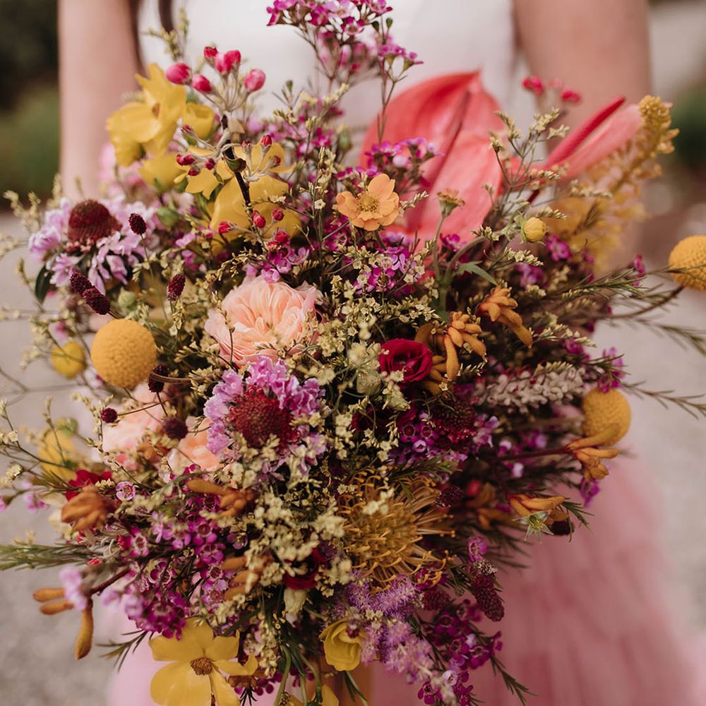 Pink and yellow wildflower wedding bouquet with anthuriums, billy buttons and carnations. 