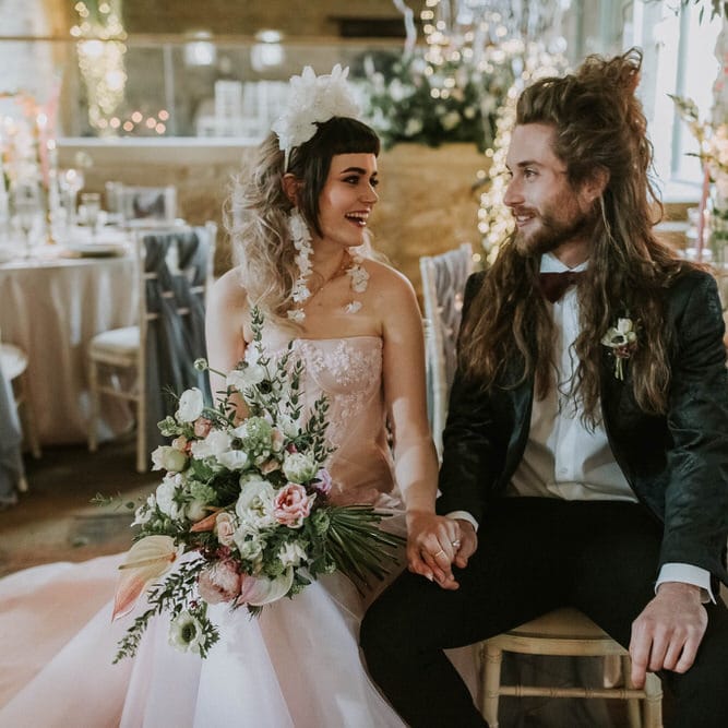 Bride in a pink strapless wedding dress and white 3D flower headband holding hands with her groom in a black tuxedo at their Hooton Pagnell wedding reception