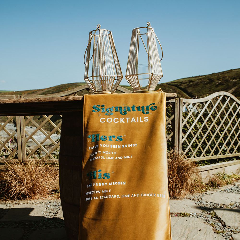 Velvet mustard coloured banner with stitched cocktail menu hangs outdoors 