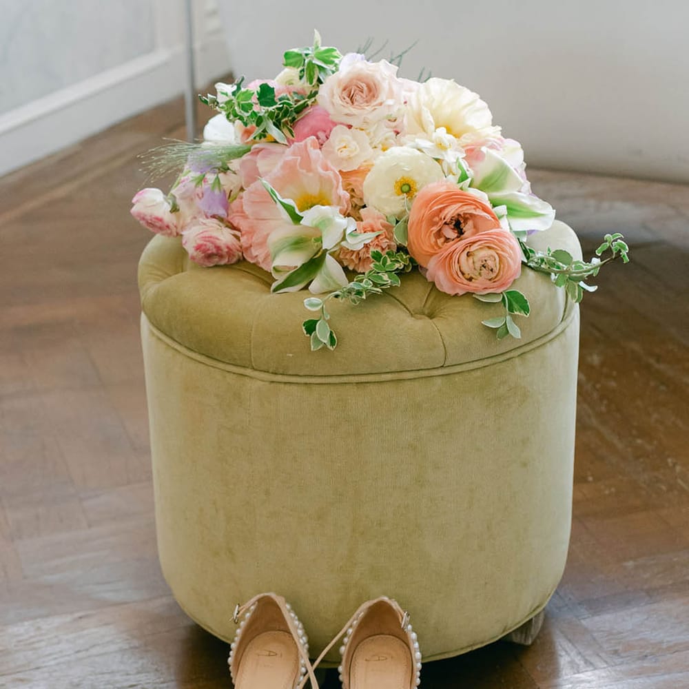 Soft pink, purple and white wedding bridal bouquet rests with the bride's pearl wedding heels 