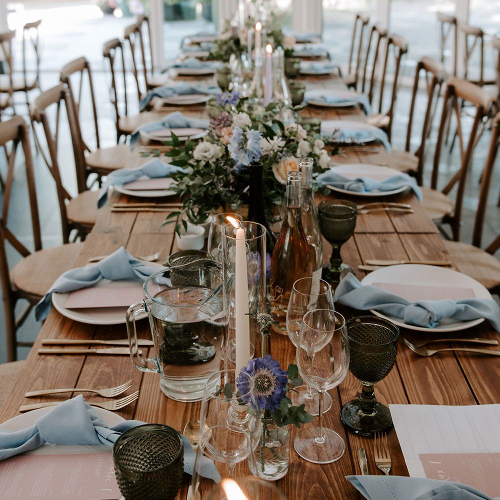 Pastel wedding flowers decorate the wedding tables with pink menus and blue napkins with coloured glassware 
