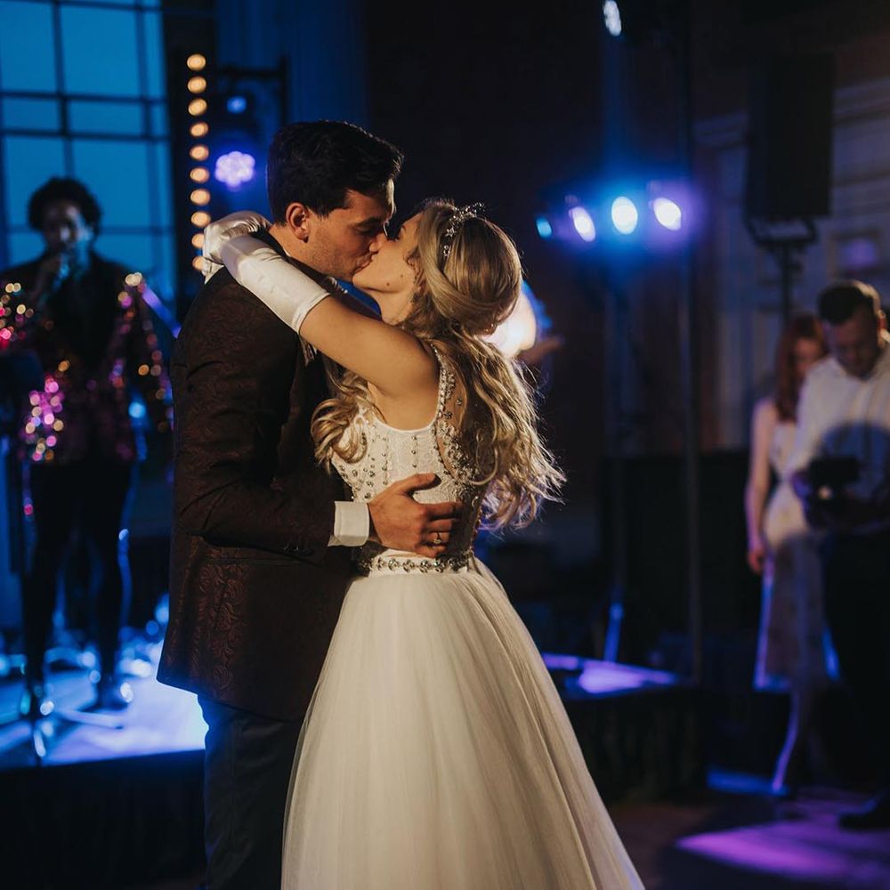 The bride changed into a princess tulle Jenny Packham wedding dress with satin gloves kissing the groom as they share their first dance together 