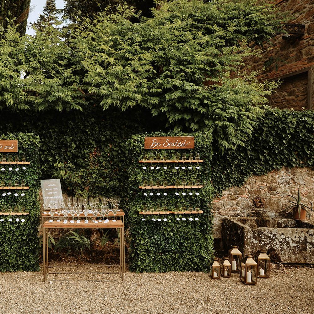 Prosecco wall reading 'sip and be seated' surrounded by greenery and lanterns at Italian villa wedding 