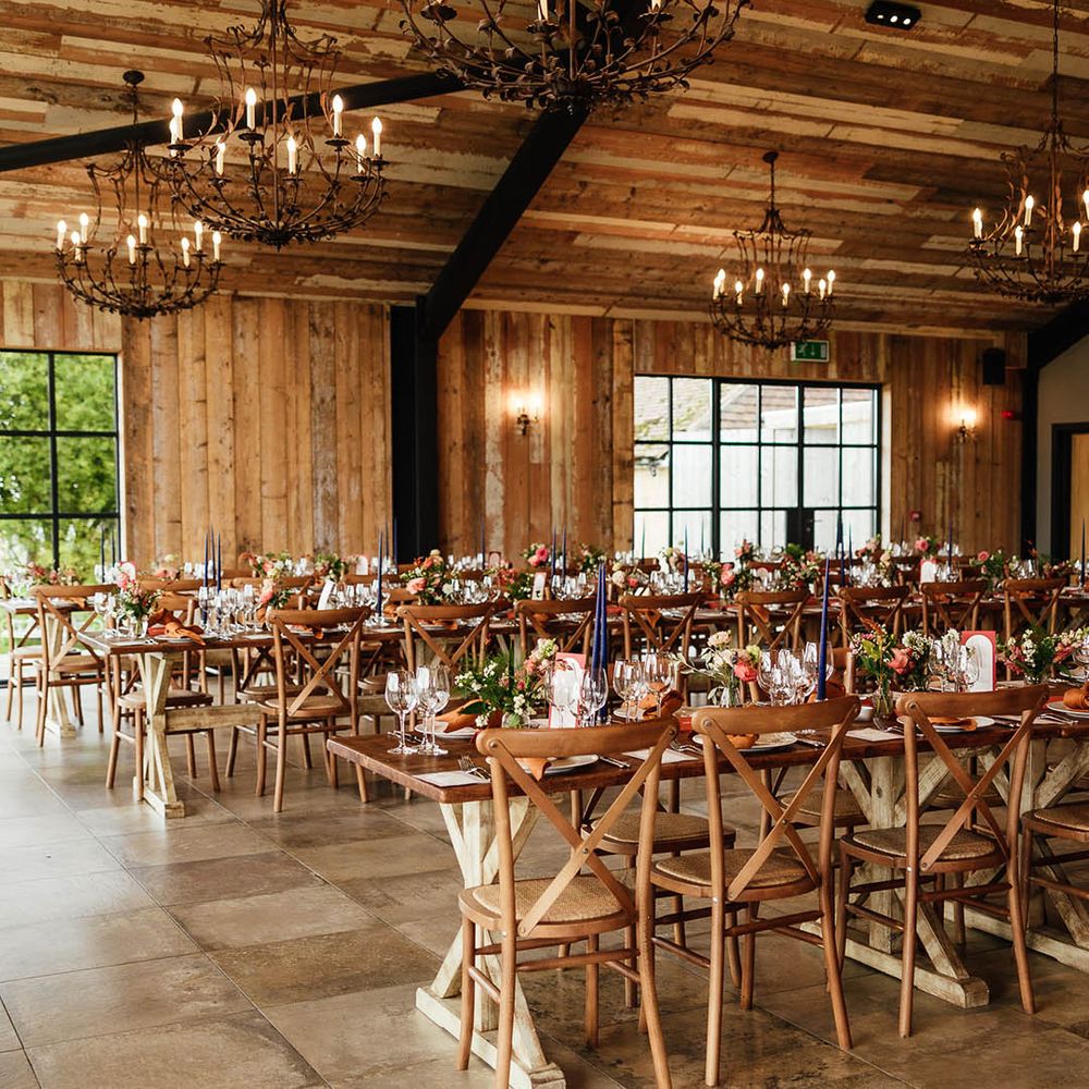 Tall blue taper candles with copper taper candles and napkins for the autumn wedding at the barn with chandeliers overhead 