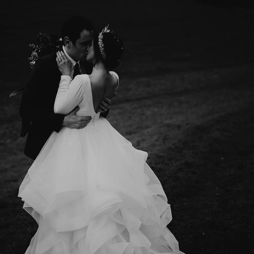 Bride in ruffle layered wedding dress kissing groom