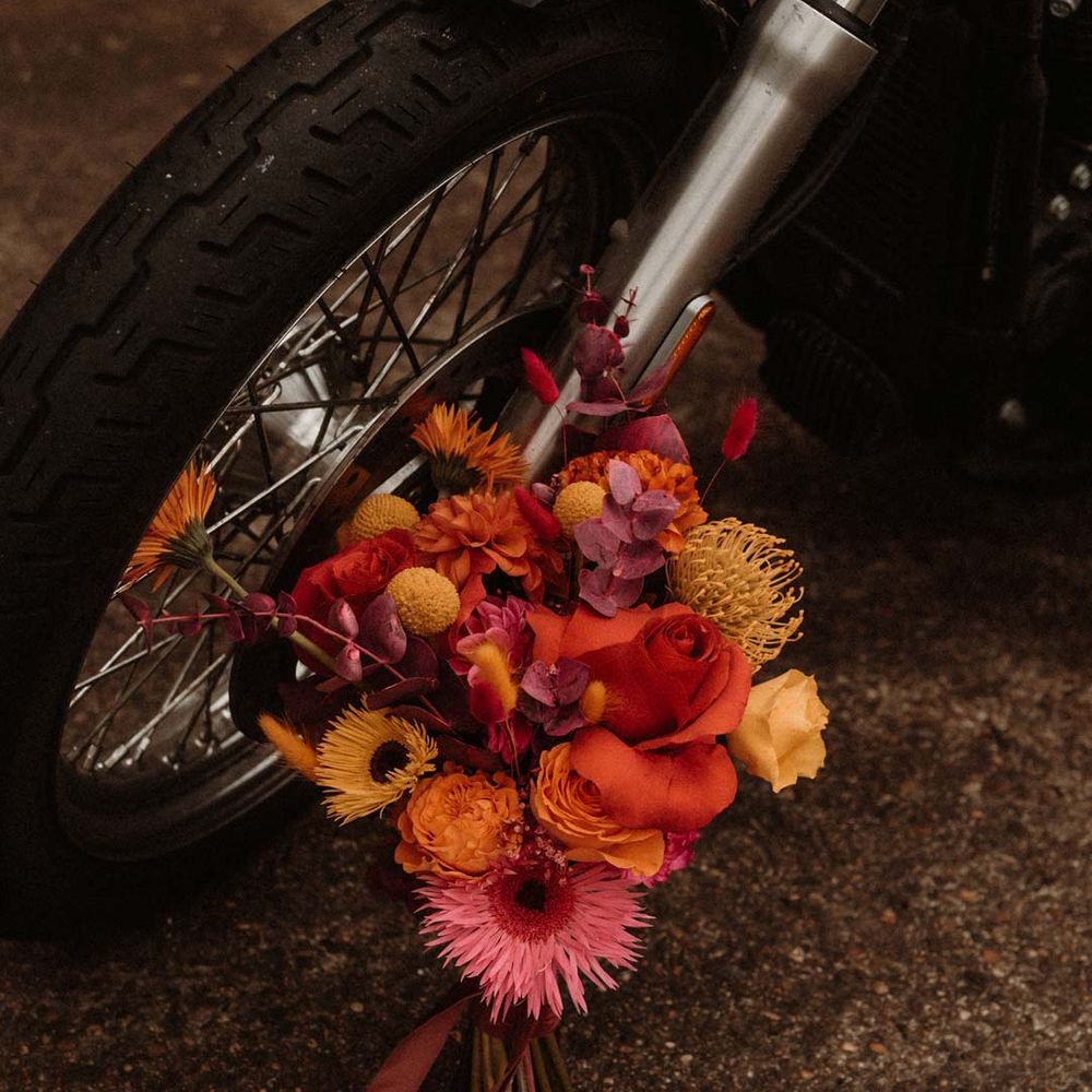 Pink red and orange vibrant wedding flowers new to wedding motorbike at German wedding editorial shoot with vinyl wedding arch