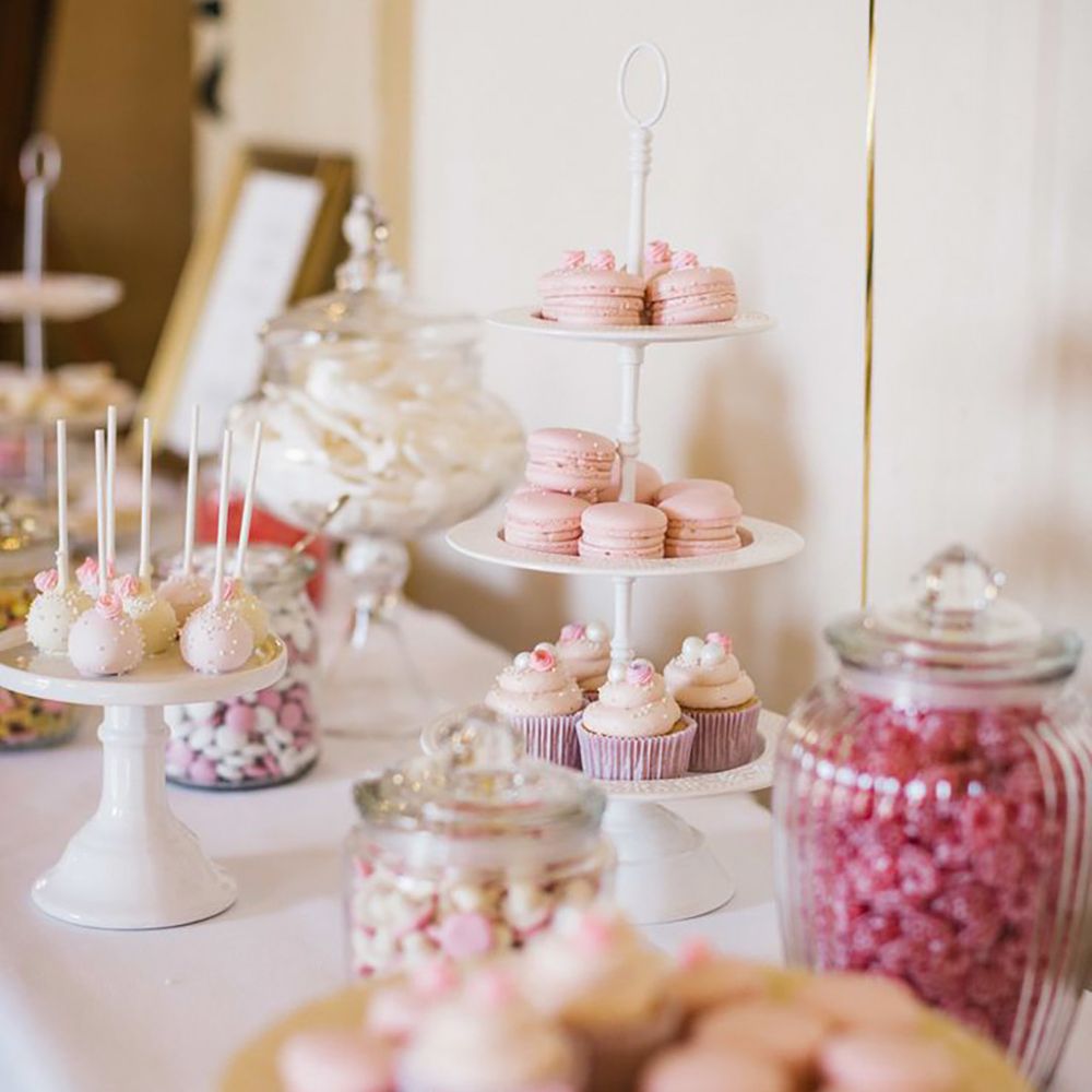 Pink theme wedding dessert table with macarons, cake pops, and pink sweets in glass jars 