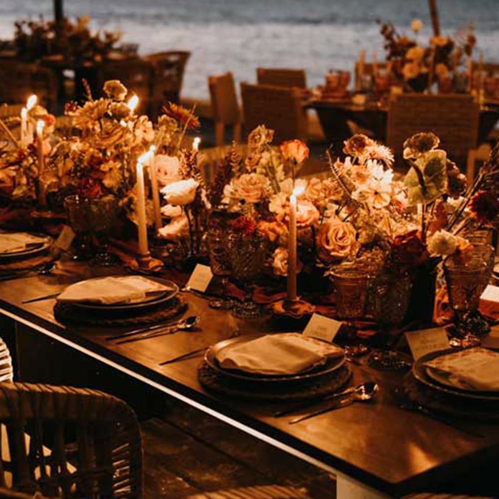Outdoor wedding tablescape for destination wedding with cosy lighting and autumnal inspired decor with autumn leaves and dried flowers 
