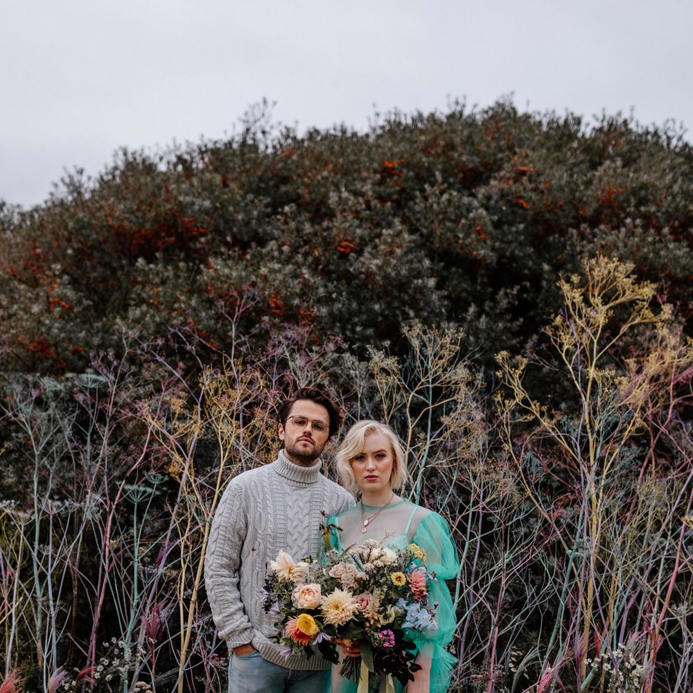 Cool bride and groom portrait on the beach at their intimate elopement with the bride in a sheer pastel wedding dress 