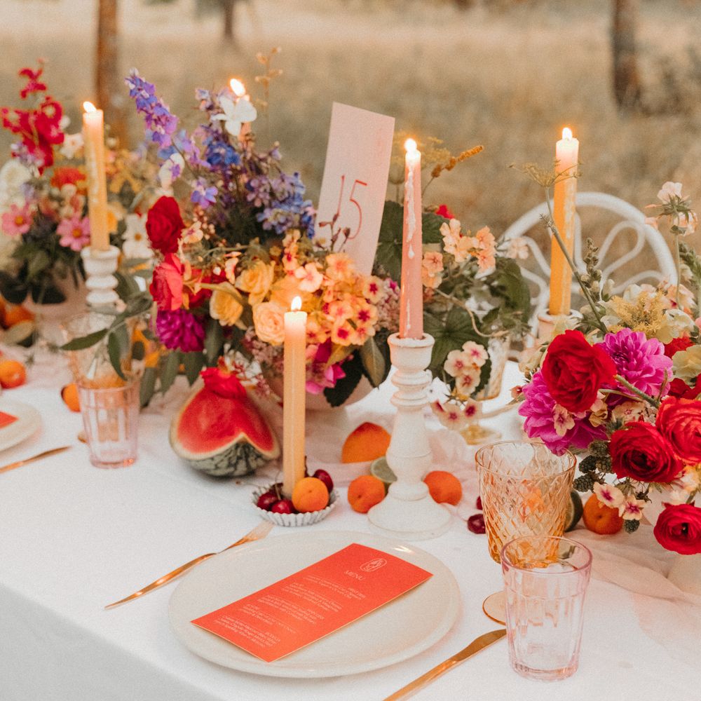 Bright & colourful tablescape complete with three floral bouquets and candles