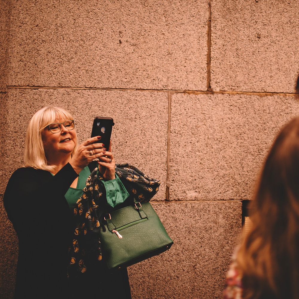 Bride & groom kiss as wedding guest takes photo on her phone