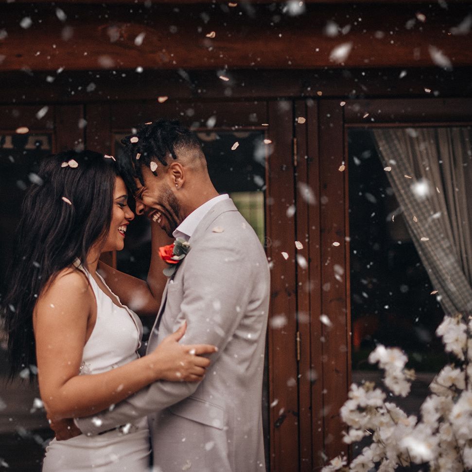 Bride & groom laugh together and confetti blows around them