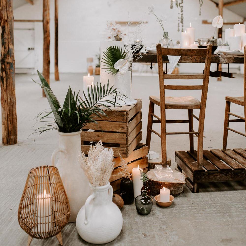 Tropical wedding set up with neutral flowers, tropical plants, wooden bar stools and crates