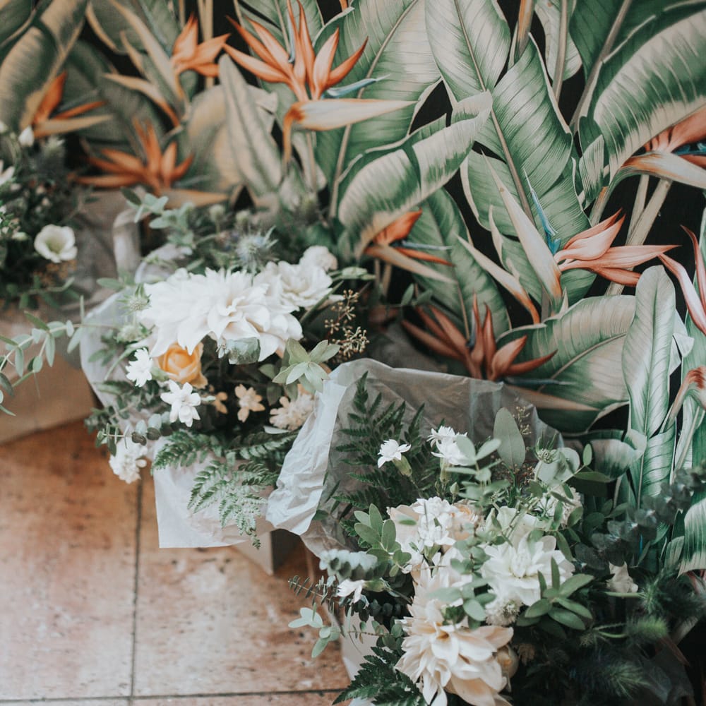 Dahlia bouquets sit in gift bags at a wedding. 