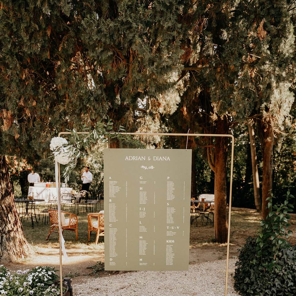 Table plan on green stationery with white writing hangs on metal complete with floral foliage decor | Royal Studio