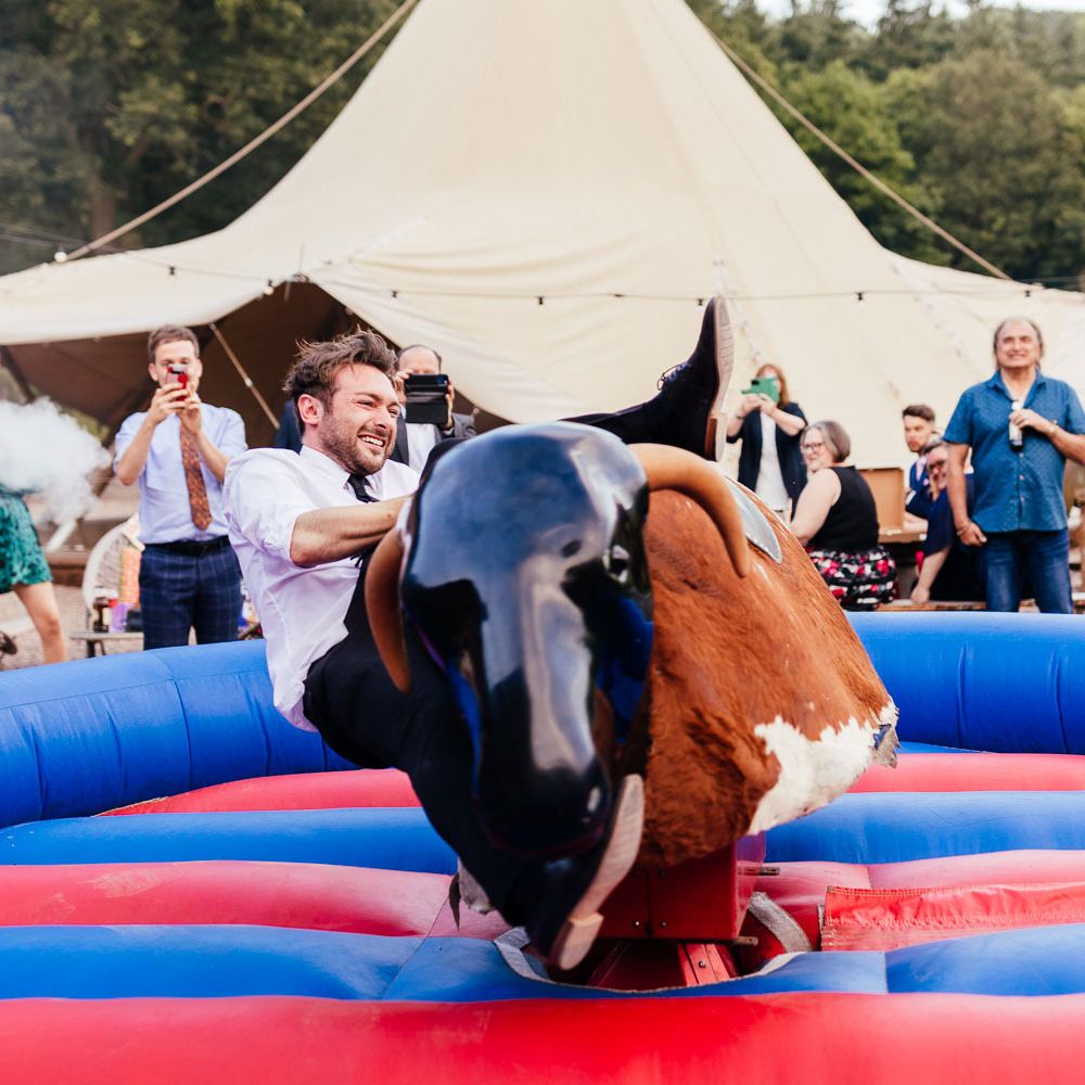 Groom in white shirt and black trousers falls off bucking bronco at The Bridal Barn in Claverley after outdoor summer wedding ceremony