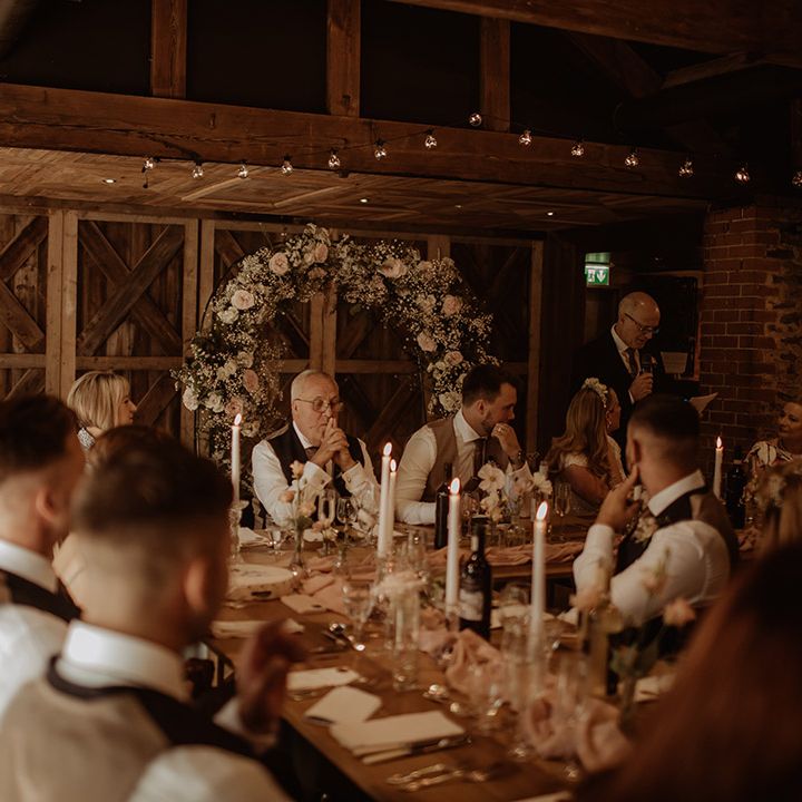 Dewsall Court wedding reception with pink flower and gypsophila flower arch behind the top table and taper candles table decor 