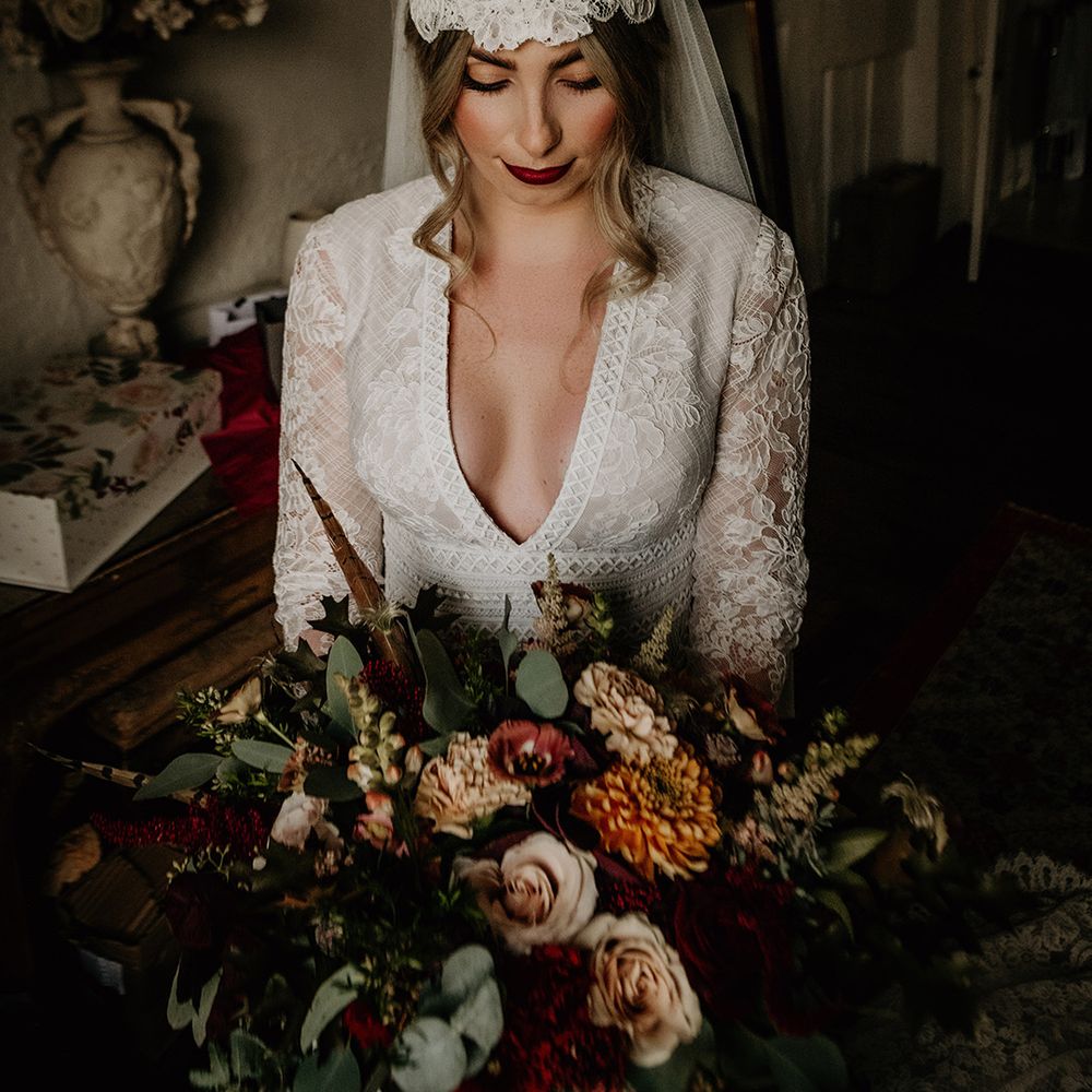 Beautiful bride with red lipstick in a lace wedding dress with plunging neckline and Juliet cap veil 