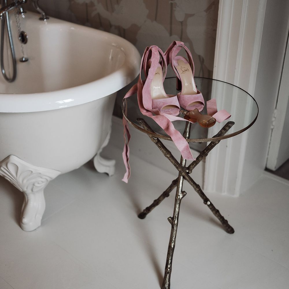 Pink Christian Louboutin wedding shoes with ribbon ankle strap on a glass table next to a roll top bath at Iscoyd Park 