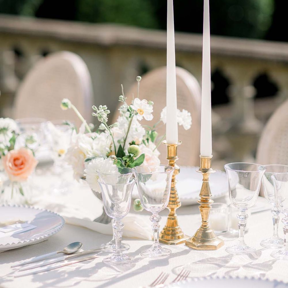 Candlesticks in golden candlestick holder on simple tablescape for outdoor reception