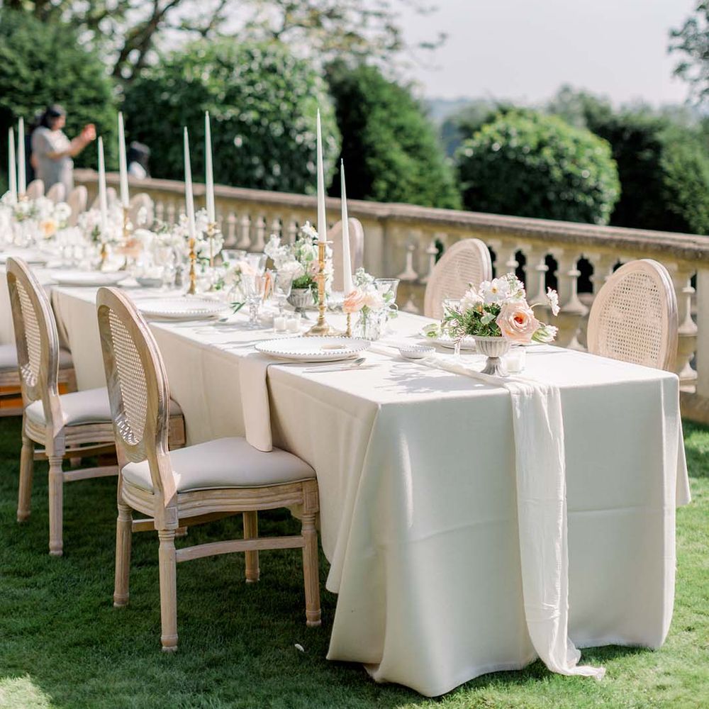 Long table complete with white table cloth and pastel florals lining the middle 
