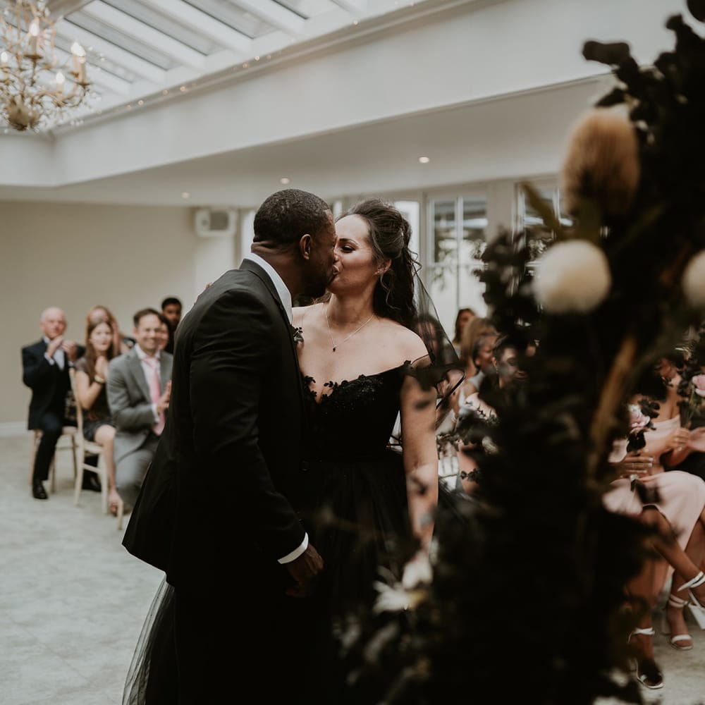 Bride & groom kiss on their wedding day as bride wears black wedding gown