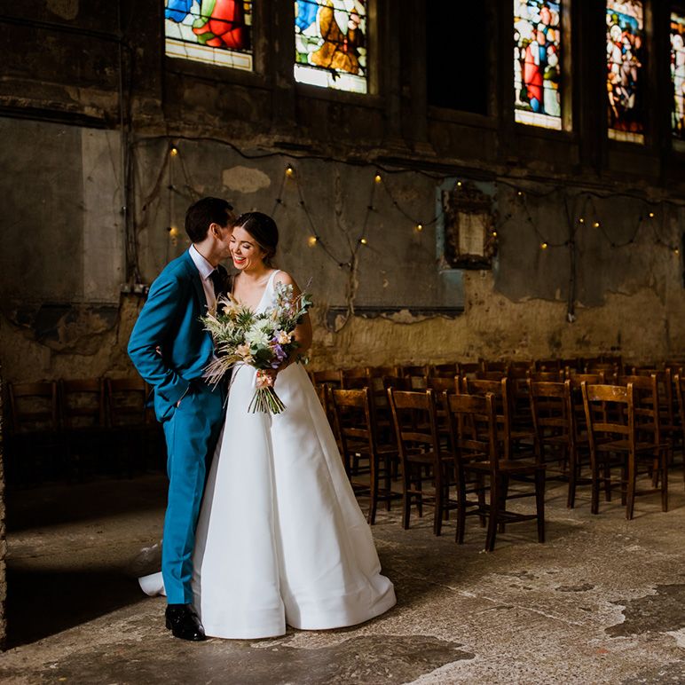 Bride and groom at the Asylum Chapel for their wedding with stained glass windows 