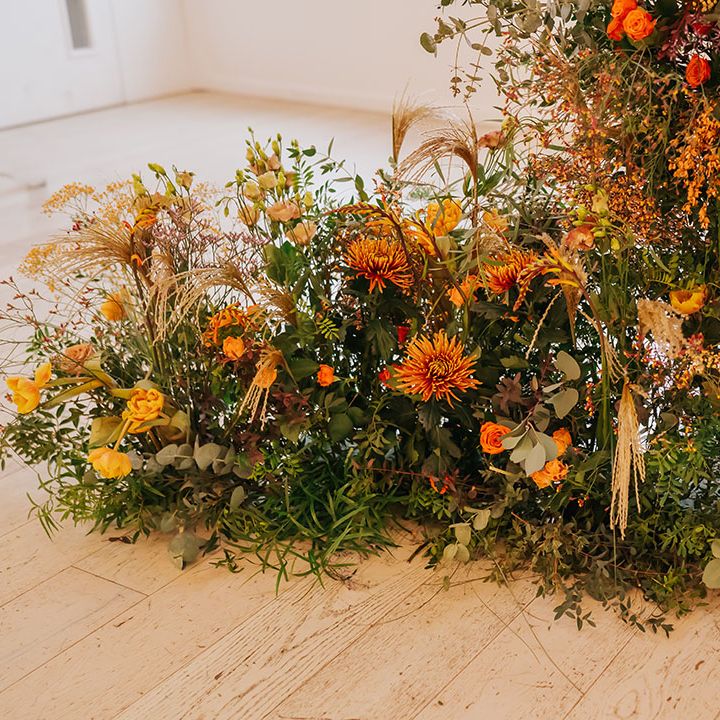 ceremony wedding flower arrangement with foliage, orange and yellow flowers