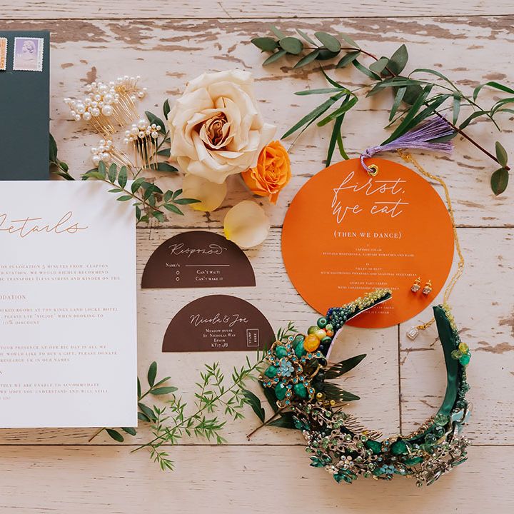 flatlay of an orange wedding stationery suite with bridal hair accessory