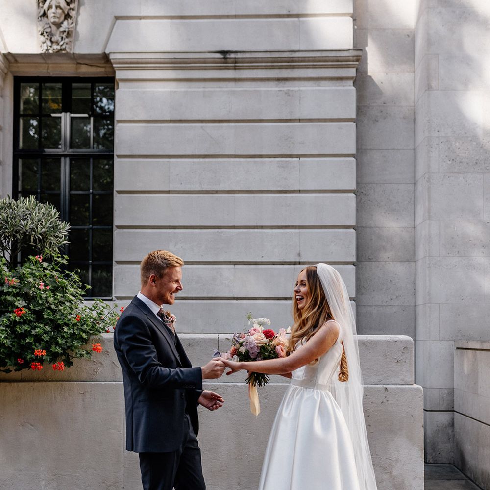 Romantic first look with groom in a dark blue suit and bride in a princess wedding dress with full skirt 