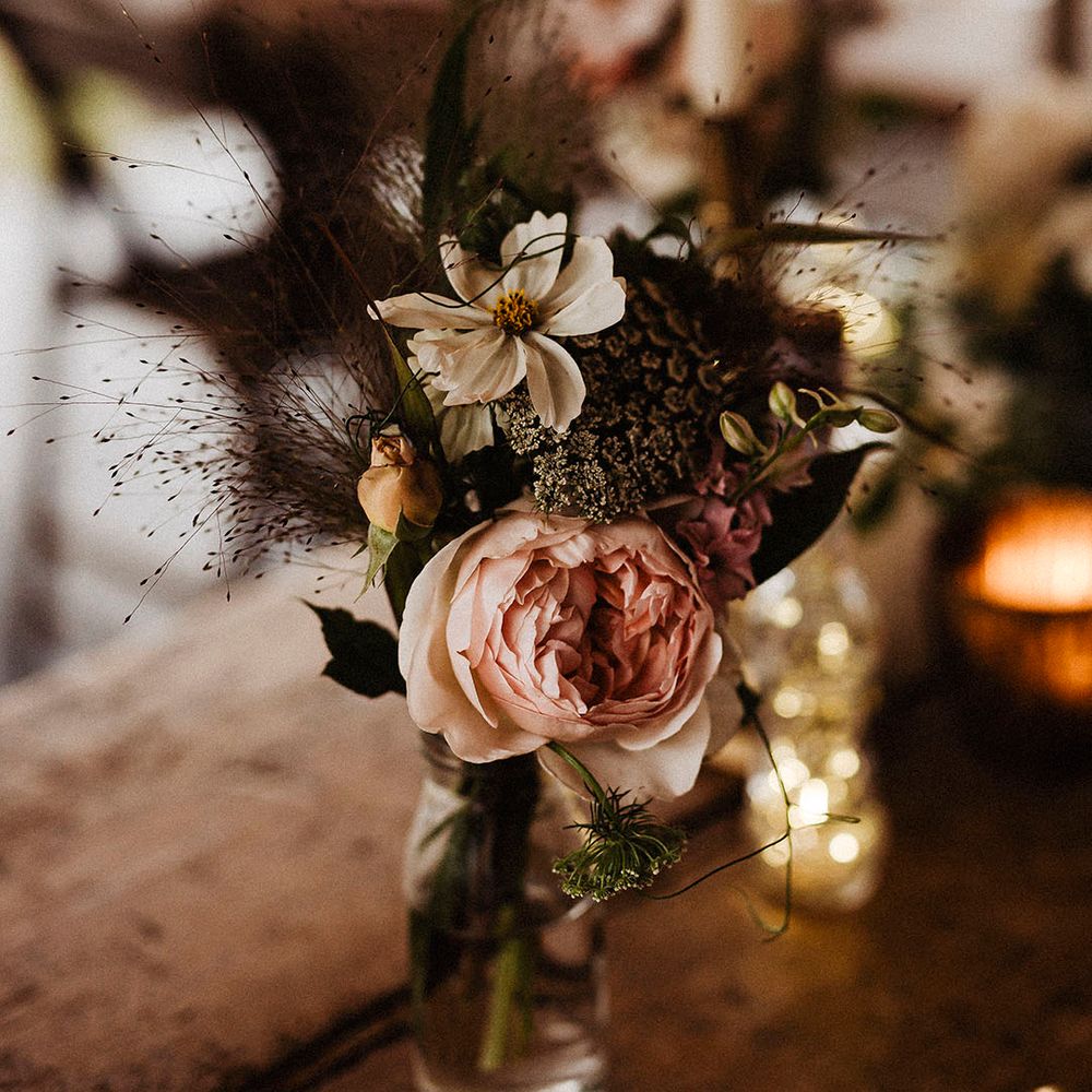 Pink rose and white cosmos with other flowers make up small flower arrangement for table setting
