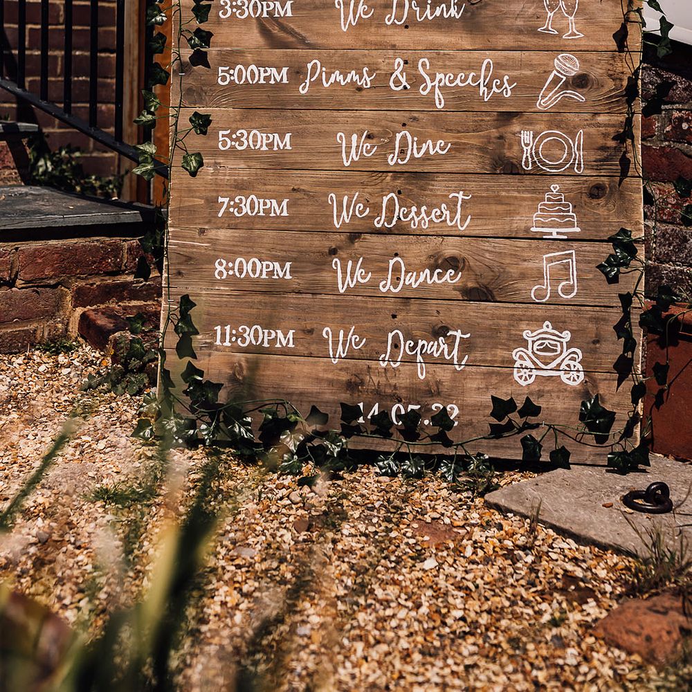 Wooden pallet board order of the day and welcome wedding sign with foliage decoration 