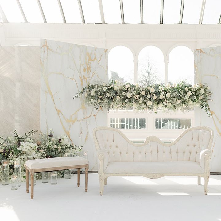 Isla Gladstone Conservatory finished with fresh white floral bouquets and green foliage and white furniture in front of large bay window