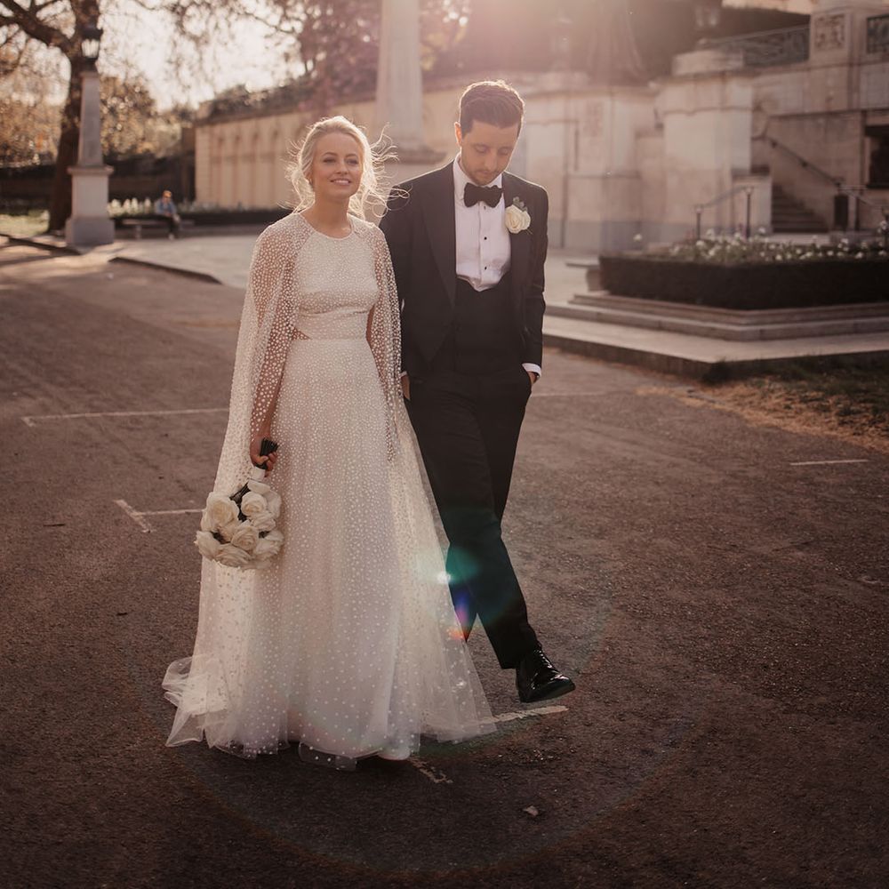 Bride in Jesus Peiro cape and wedding dress with groom in black tie 