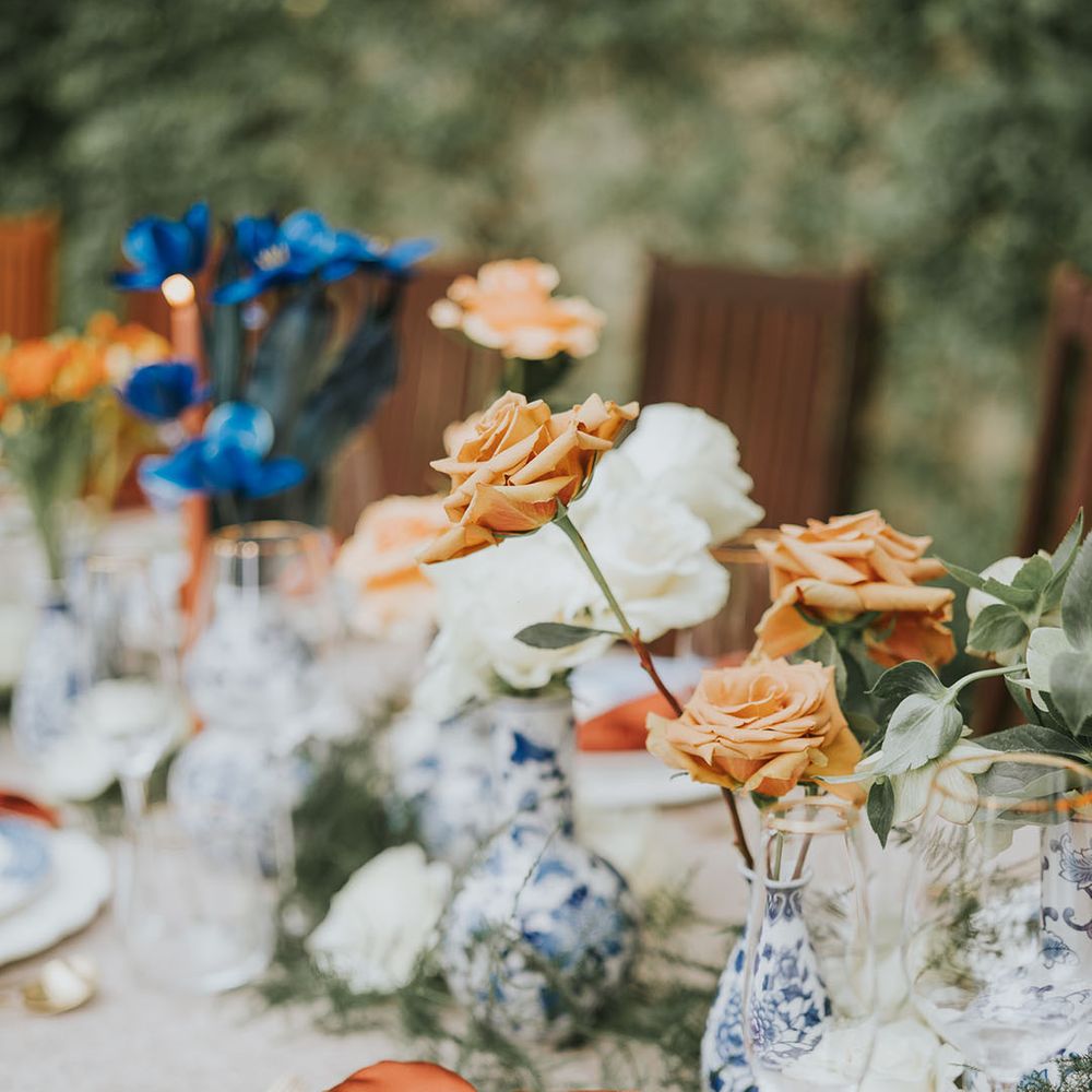 Blue and white sorcery and vases with orange napkins and blue and orange wedding flowers 