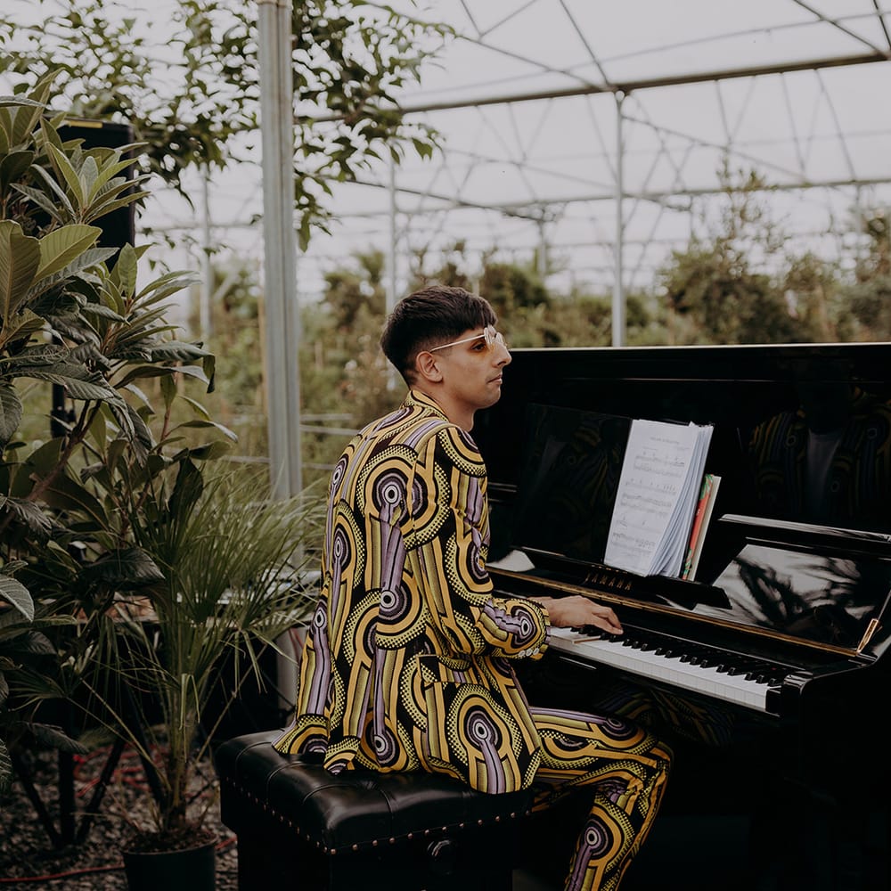 Bride's brother plays piano during ceremony whilst wearing a colourful patterned suit