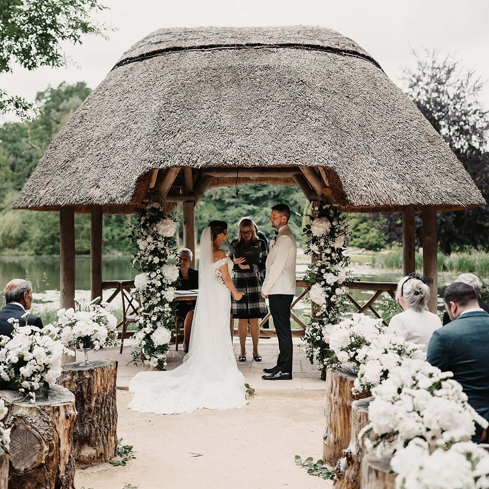 Classic and elegant white flowers line the aisle and decorate the altar in flower columns for the bride and groom's timeless traditional wedding 