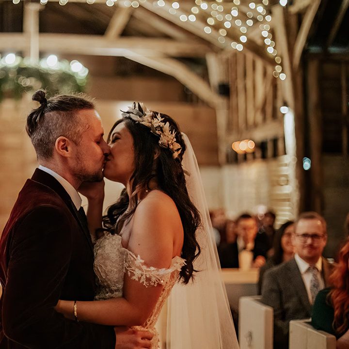 The bride and groom share their first kiss as a married couple for a boho autumnal barn wedding 