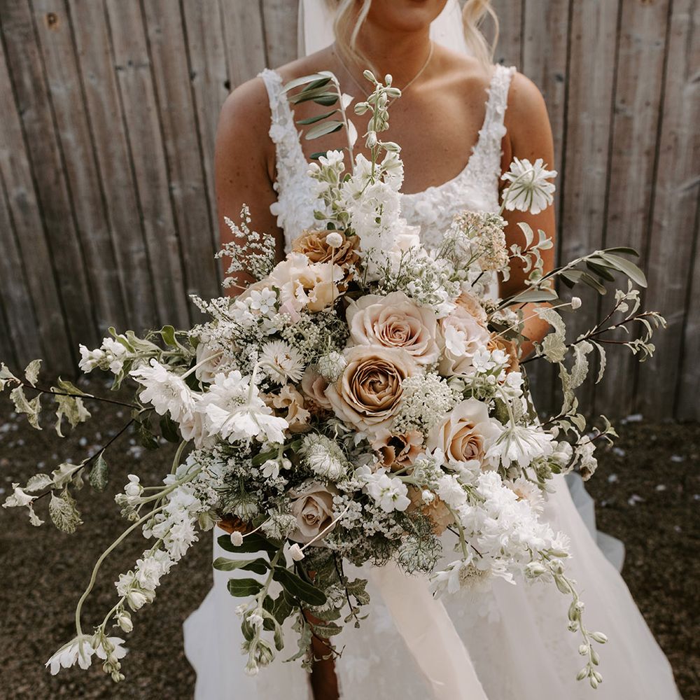 Oversized neutral colour wedding bouquet for the bride with roses, foliage, and white flowers 