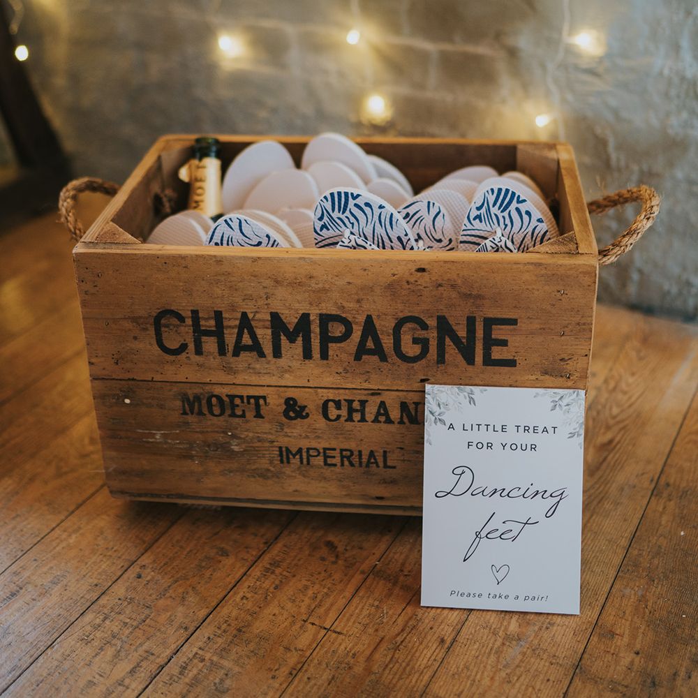 Rustic wooden box full of flip flops with a sign fro guests to help themselves to the flip flop wedding favours 