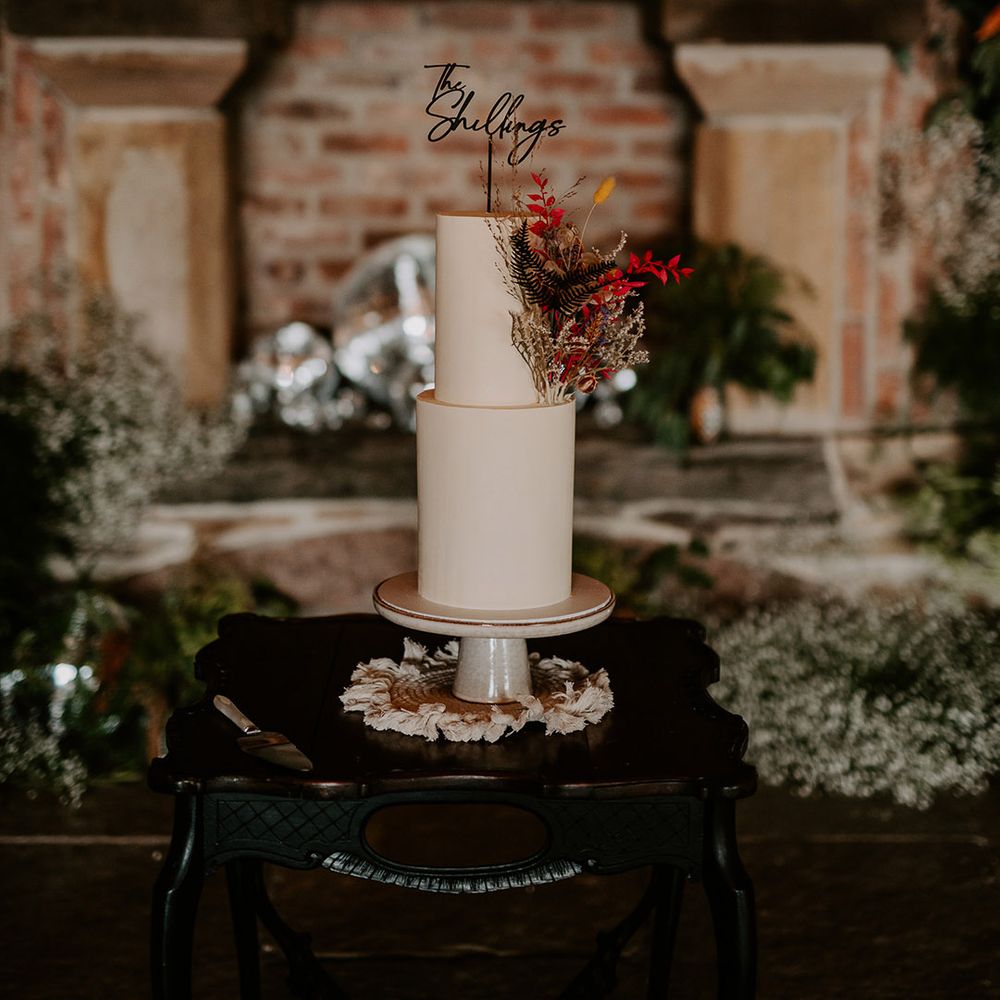 Two tier white buttercream wedding cake decorated with a black cake topper 
