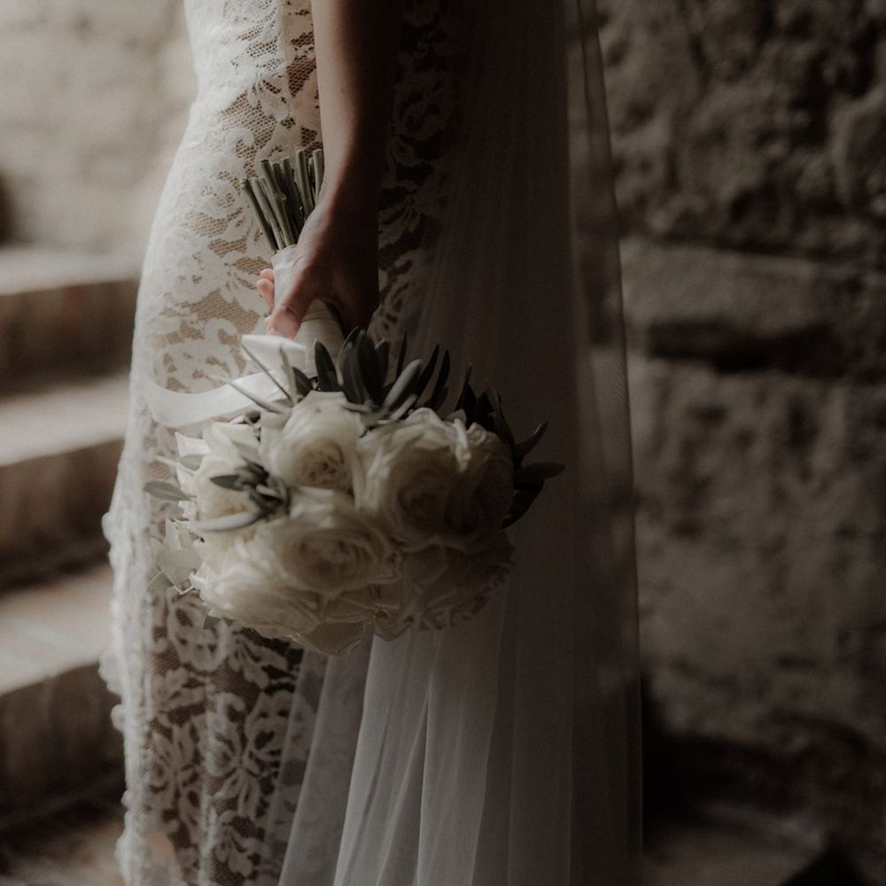 Bride in lace gown holding white rose wedding bouquet 