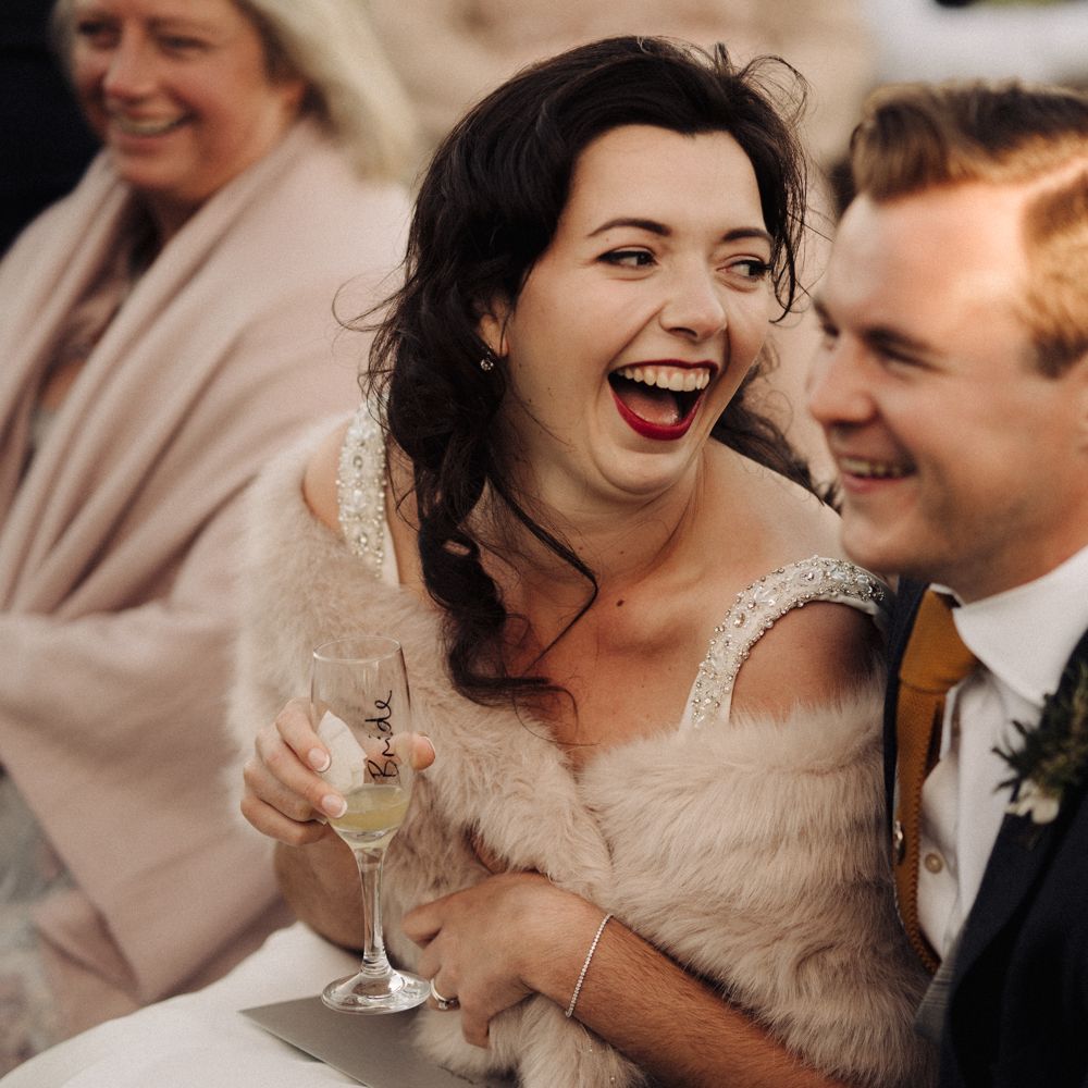 Bride & groom laugh during wedding reception speeches