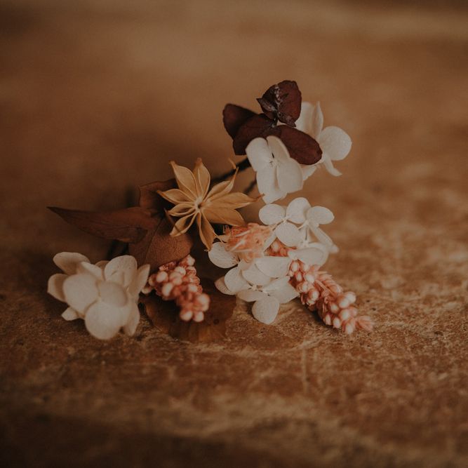 Delicate buttonhole with white and brown flowers and leaves
