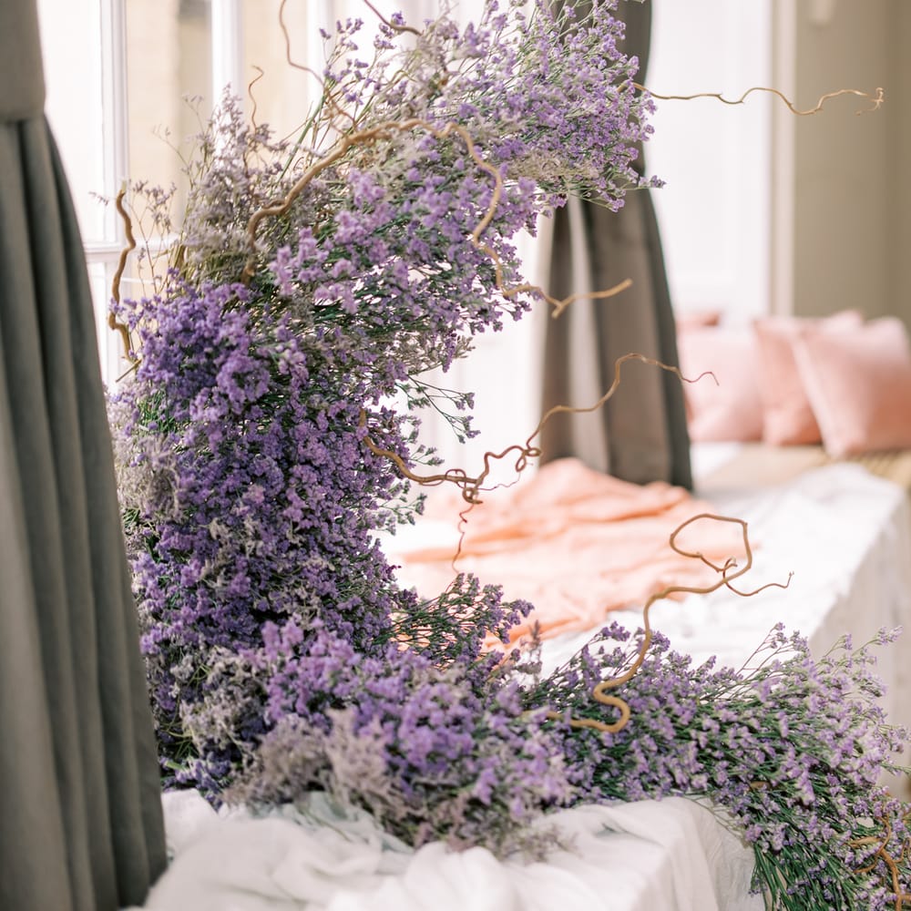 Lavender comes out of window whilst twisted branches weave in and out of floral installation 