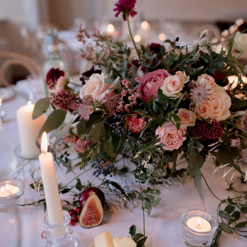 Romantic blush pink and peach floral centrepiece with candle light and figs