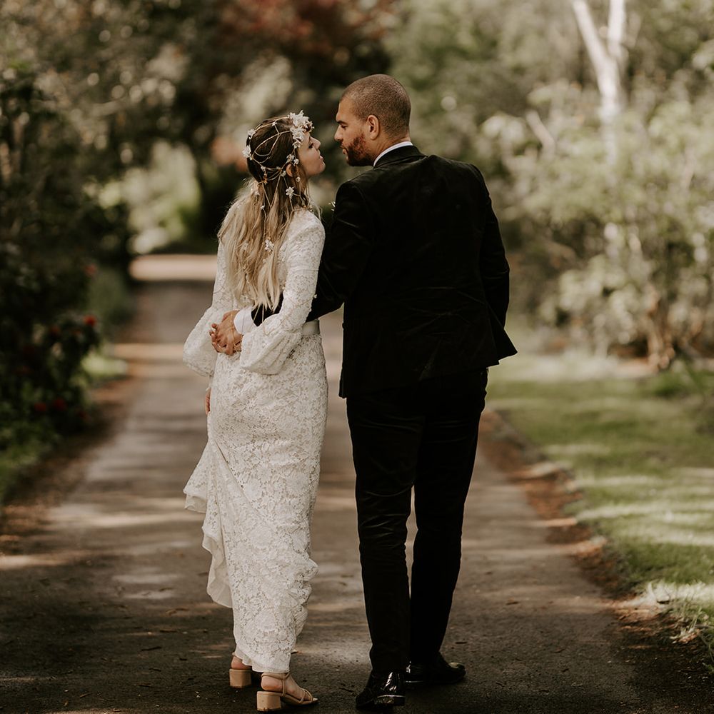 Groom in a black suit kissing his bride in a lace wedding dress on the grounds of Waresley Park Estate 