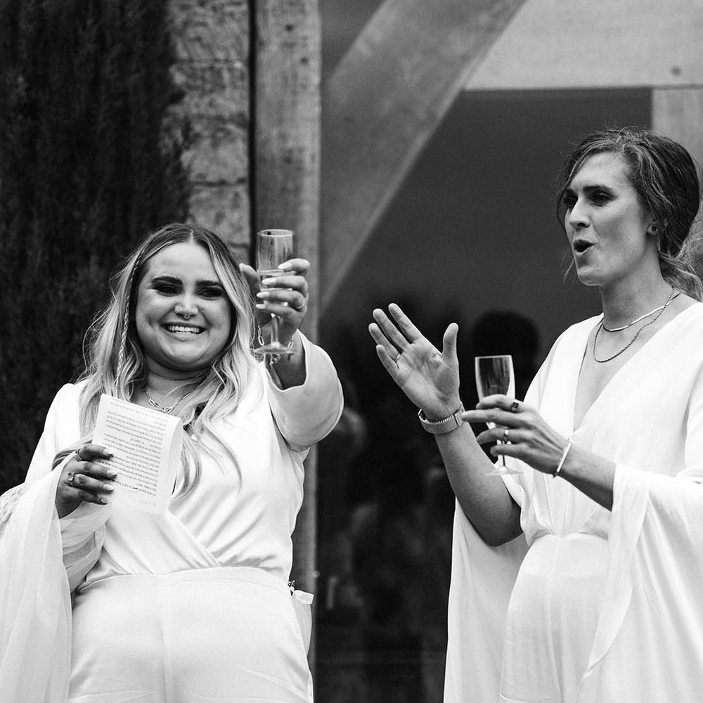 Black & white image of brides celebrating outdoors on their wedding day