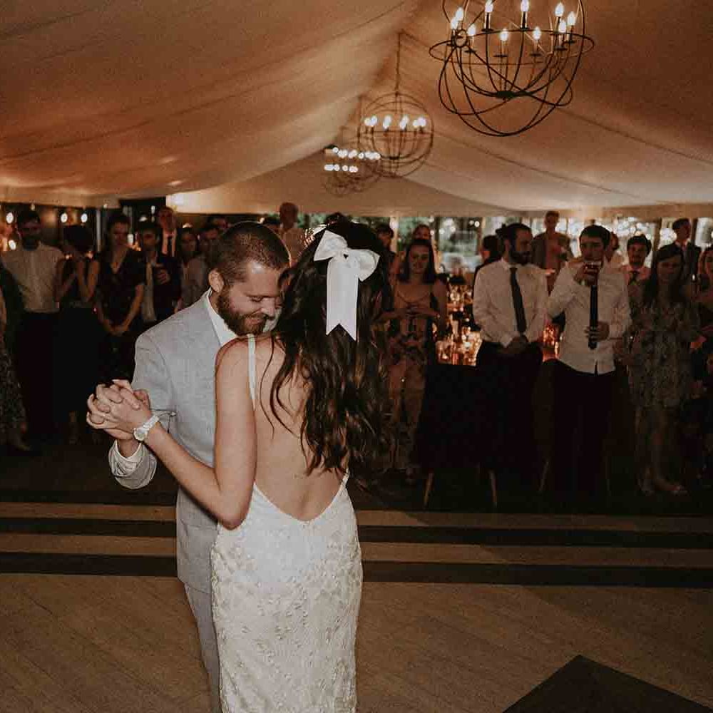 Bride in low back wedding dress with satin hair bow dances with her new husband