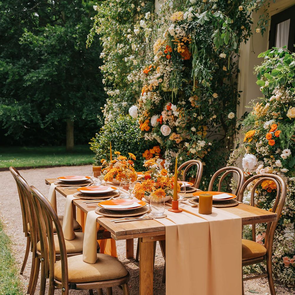 Orange pillar and taper candles, natural wicker place mats and orange tableware 